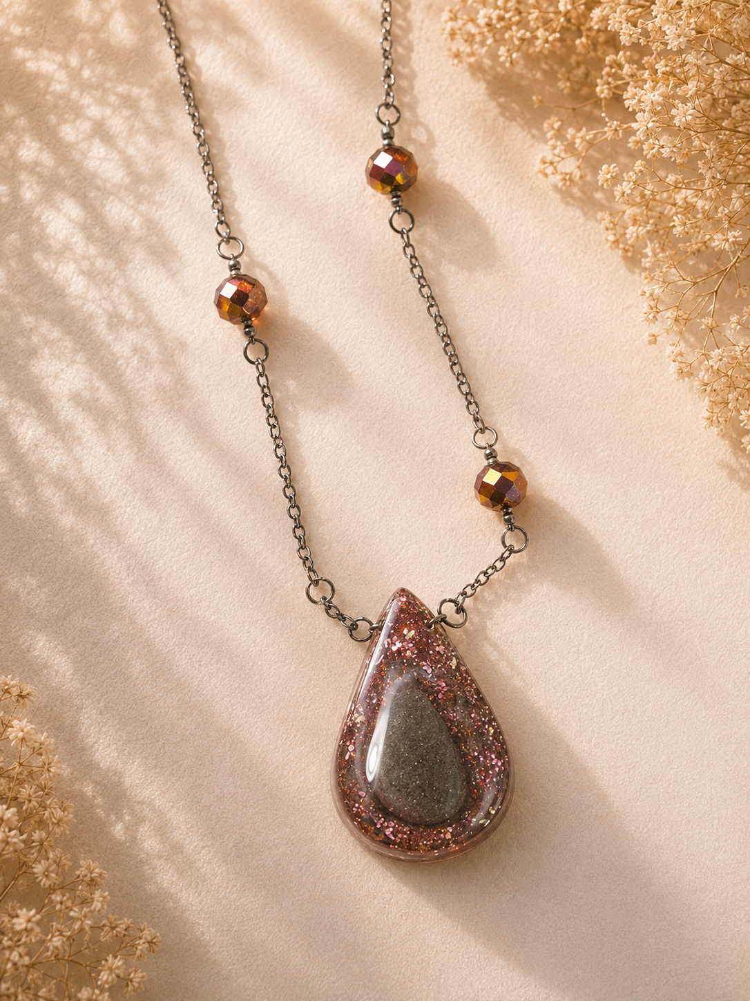 Rose gold glitter teardrop cremation memorial necklace with double pour resin pendant and crystal bead accents on gunmetal chain