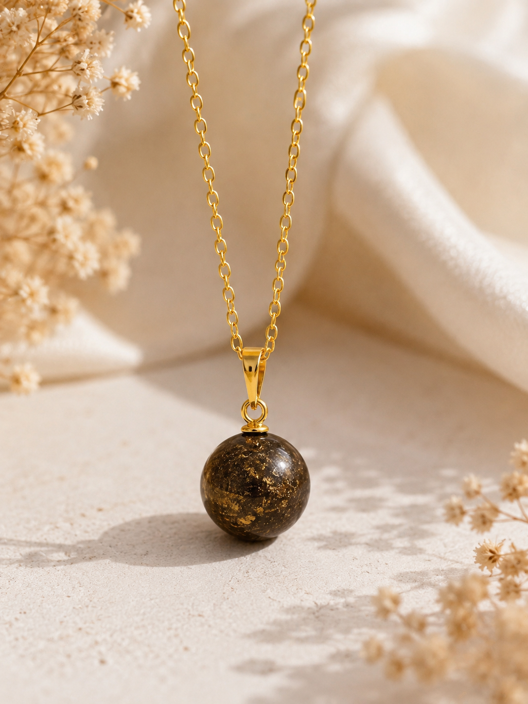 Gold sphere cremation memorial necklace with dark resin ball pendant and gold foil flakes on delicate gold chain