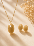 Matching oval cremation memorial jewelry set with gold chain necklace and stud earrings in natural ash-tone resin